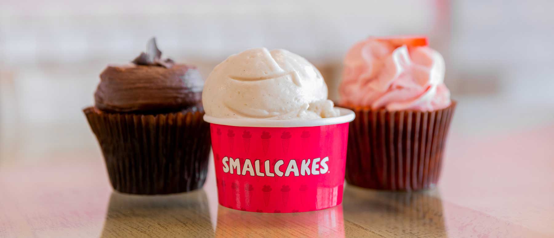 Ice Cream in Smallcakes logo cup with two cupcakes